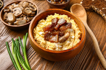 Bowl of tasty banosh on wooden background