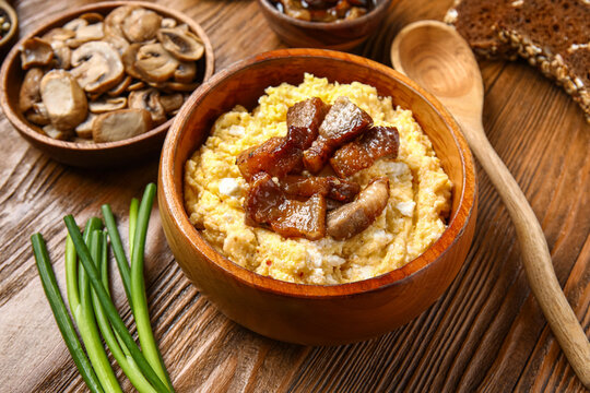 Bowl of tasty banosh on wooden background