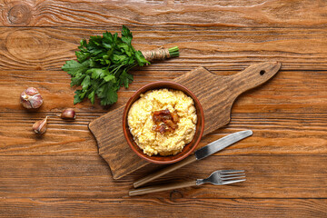 Bowl of tasty banosh on wooden background