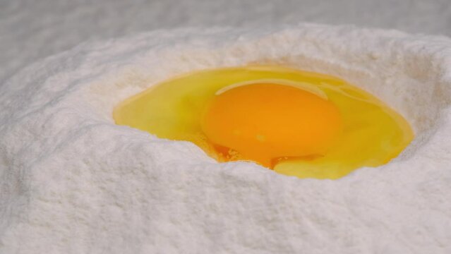 Broken chicken egg in flour, close-up. The process of preparing dough.
