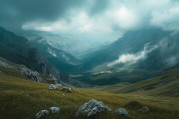 Misty mountain landscape with a lush green valley under a cloudy sky.