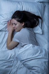 A beautiful girl is sleeping in a bed with a white sheet