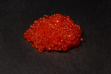 Red trout caviar on a black background.