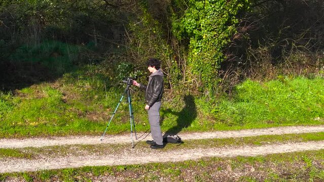 Nature Photographer With Camera On Tripod. aerial orbiting shot