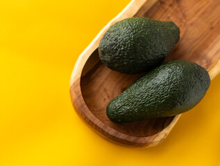 two haas avocados on a long wooden plate