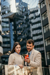 Businessman and businesswoman converse in city center