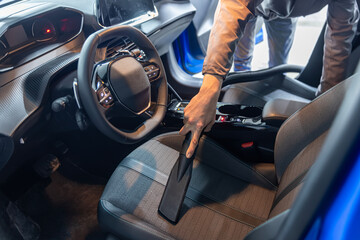 Car interior luxury service. Details of car cleaning male using professional steam vacuum for dirty...