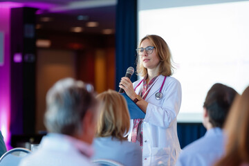 Female doctor as speaker at conference for healtcare workers, medical team sitting and listening presenter. Medical experts attending an education event, seminar in board room. - Powered by Adobe