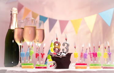 Birthday with champagne and glasses. Birthday candle with number 83. Anniversary card with garlands...