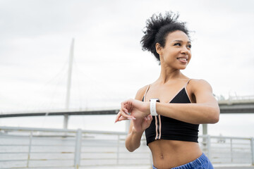 Fit woman with fitness tracker ready for a run on a bridge, urban health concept.