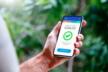 Man making money transfers online using apps to send and receive currency. Mobile phone with a financial application on screen. Money transfer concept.