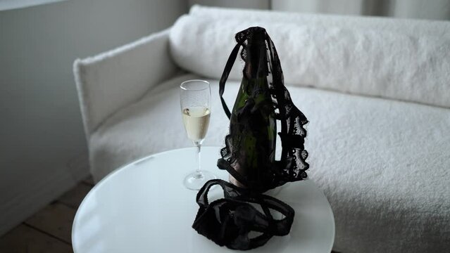 romantic date of a couple with two glasses of champagne, romance and love. The girl takes off and throws her black lace underwear, panties and bra on the table. Seduction and foreplay before sex