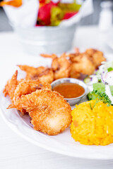 crispy coconut shrimp with sweet and sour dressing and salad on the side and yellow rice, Mexican style, inside a white restaurant.