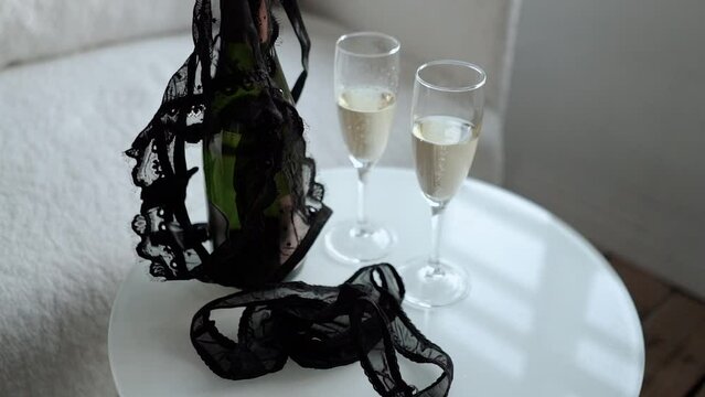 romantic date of a couple with two glasses of champagne, romance and love. The girl takes off and throws her black lace underwear, panties and bra on the table. Seduction and foreplay before sex