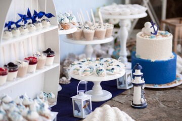 Dessert table for a party. Cake, cupcakes, sweetness and flowers. Maritim theme candy bar.
