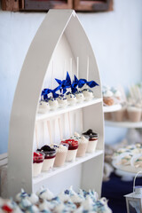 Dessert table for a party. Cake, cupcakes, sweetness and flowers. Maritim theme candy bar.