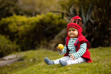 Un bebé sonriente con su chullo tejido, disfrutando del sabor de la naranja, pequeño tesoro...