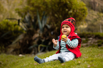 Un bebé sonriente con su chullo tejido, disfrutando del sabor de la naranja, pequeño tesoro...