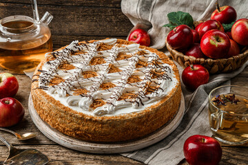 Delicious biscuit cake with cream and apples on wooden rustic background with cup of tea, fresh...
