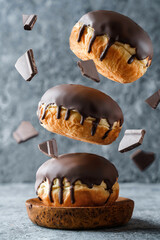 Donuts with chocolate glaze and chocolate pieces frozen in motion on grey stone background. Sweets, dessert and pastry, close up