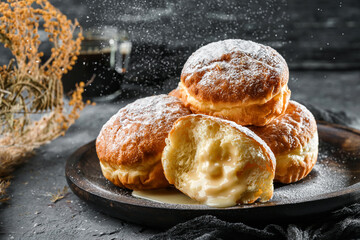 Donuts with custard and powdered sugar on dark stone background. Sweets, dessert and pastry, top...