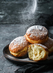 Donuts with custard and powdered sugar on dark stone background. Sweets, dessert and pastry, top...