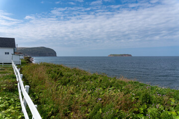 Fototapeta na wymiar Mainland (La Grand'terre) coast line on Port au Port Peninsula in Newfoundland, Canada. Red Island (L'Île Rouge), Sisters’ Dream School Museum, white fence, 