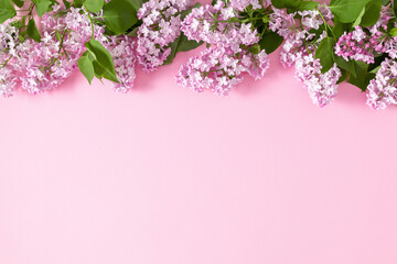 Spring lilac flowers. Frame made of lilac branches with leaves on pink background. Flat lay, top view, copy space