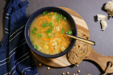 Top view of vegetarian yellow peas soup in bowl with slices of olive bread