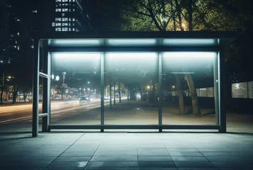  a bus stop with a glass wall and trees and a road © ion