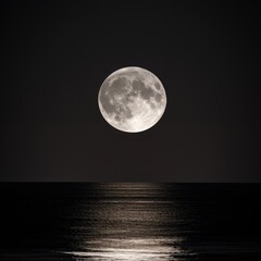 A full moon rising over the ocean at night.