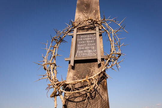 Crown of thorns surrounding plaque of John 1:29 Bible Verse on wooden cross