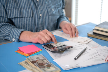 Woman work with financial papers at home count on calculator before paying taxes receipts . woman...