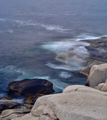 The Rough waters and crashing waves around the granite rocks at Peggys Cove in Nova Scotia on a Foggy and Misty summer day - 736653273