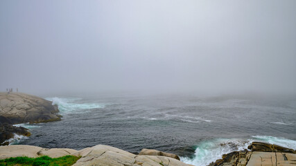 The Rough waters and crashing waves around the granite rocks at Peggys Cove in Nova Scotia on a Foggy and Misty summer day - 736653422