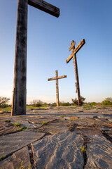 Three wooden crucifix crosses on stone and grass vertical