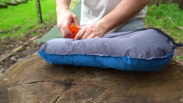Blowing up portable camping pillow with electric air pump at campground