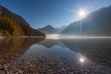Foggy mood and reflection of mountains in mountain lake, sun star, backlight, morning light, autumn, Heiterwanger See, Tyrol, Austria, Europe