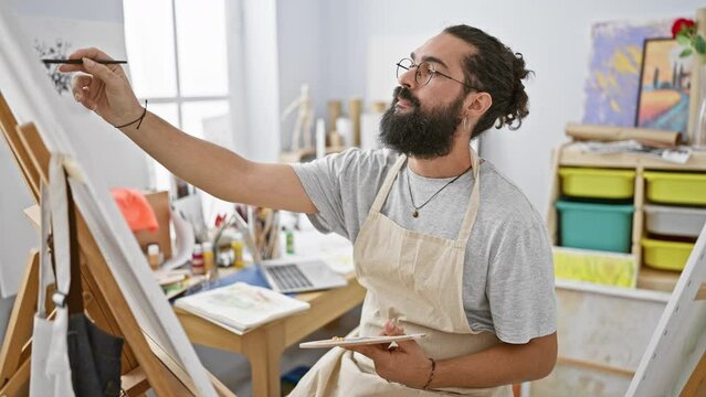 A bearded man painting attentively on a canvas in an art studio, exemplifying creativity and the artistic process.