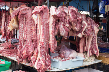Raw pork meat hanging on a butcher;s stall in Khlong Toei wet market, Bangkok, Thailand