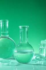 Laboratory analysis. Different glassware on table against green background