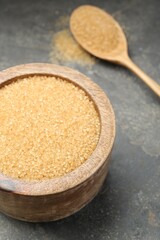 Brown sugar in bowl on grey table, closeup