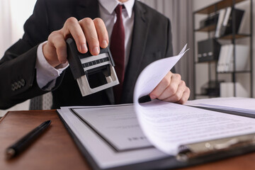 Notary stamping document at table in office, low angle view