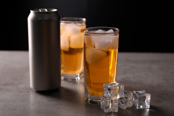 Energy drink in glasses, aluminium can and ice cubes on grey table