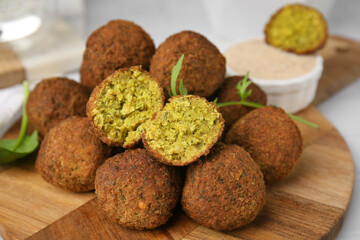 Delicious falafel balls, herbs and sauce on table, closeup