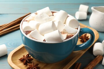 Tasty hot chocolate with marshmallows on light blue wooden table, closeup