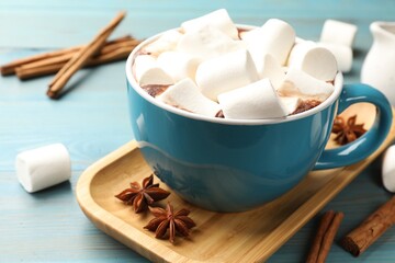 Tasty hot chocolate with marshmallows on light blue wooden table, closeup