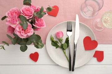 Romantic place setting with flowers and red paper hearts on white wooden table, flat lay. St. Valentine's day dinner