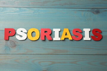 Word Psoriasis made of paper letters on light blue wooden table, top view
