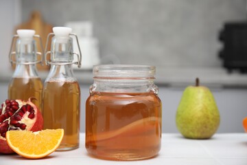 Homemade fermented kombucha and fresh fruits on white table in kitchen